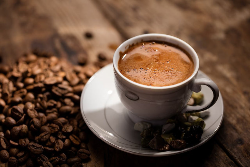Türk kahvesi faydaları ile ön plana çıkan bir fincan kahve ve yanındaki kahve çekirdekleri